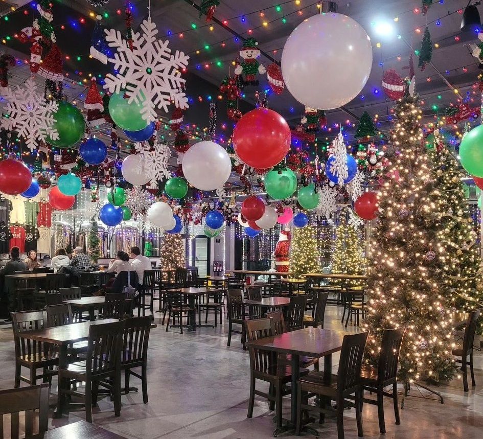 Inside view of 785 Beer Co’s Snow Globe Experience in Topeka, Kansas, showcasing sparkling holiday lights, festive decorations, and cozy seating with holiday-themed drinks