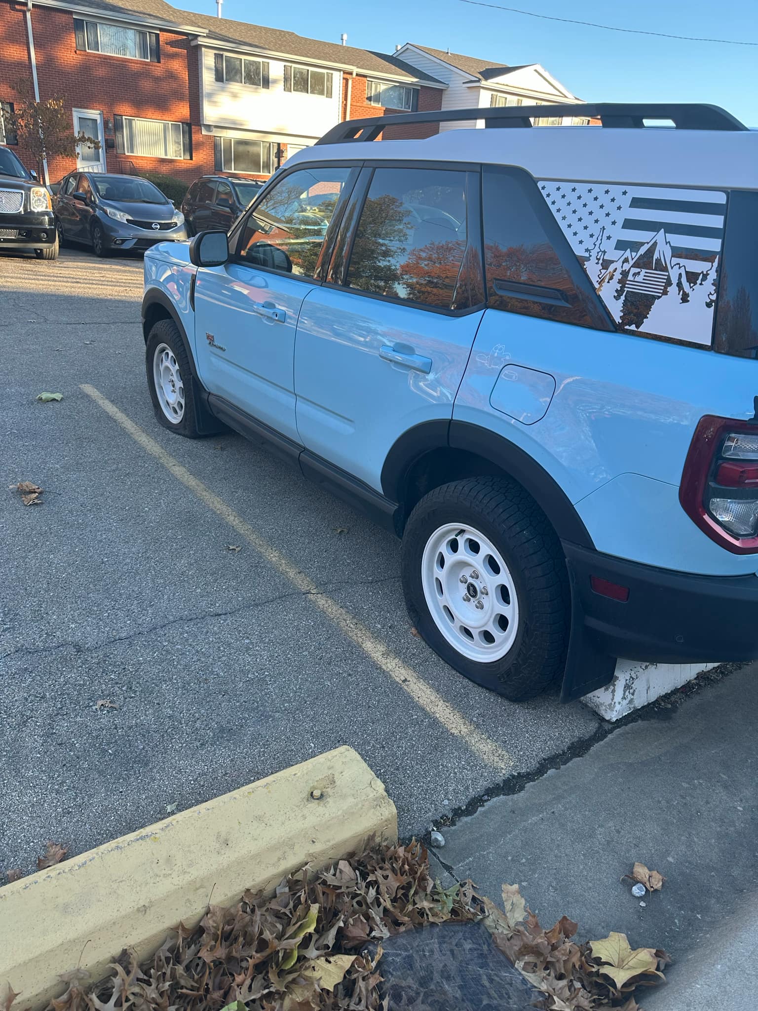 Light blue Ford Bronco Sport with slashed tires parked in front of Colonial Park Townhomes in Topeka, KS