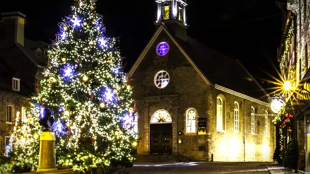 Christmas lights adorning the exterior of a church at night, with a peaceful, glowing atmosphere. The church steeple is illuminated, and festive decorations enhance the serene winter scene, evoking a sense of warmth and community during the holiday season