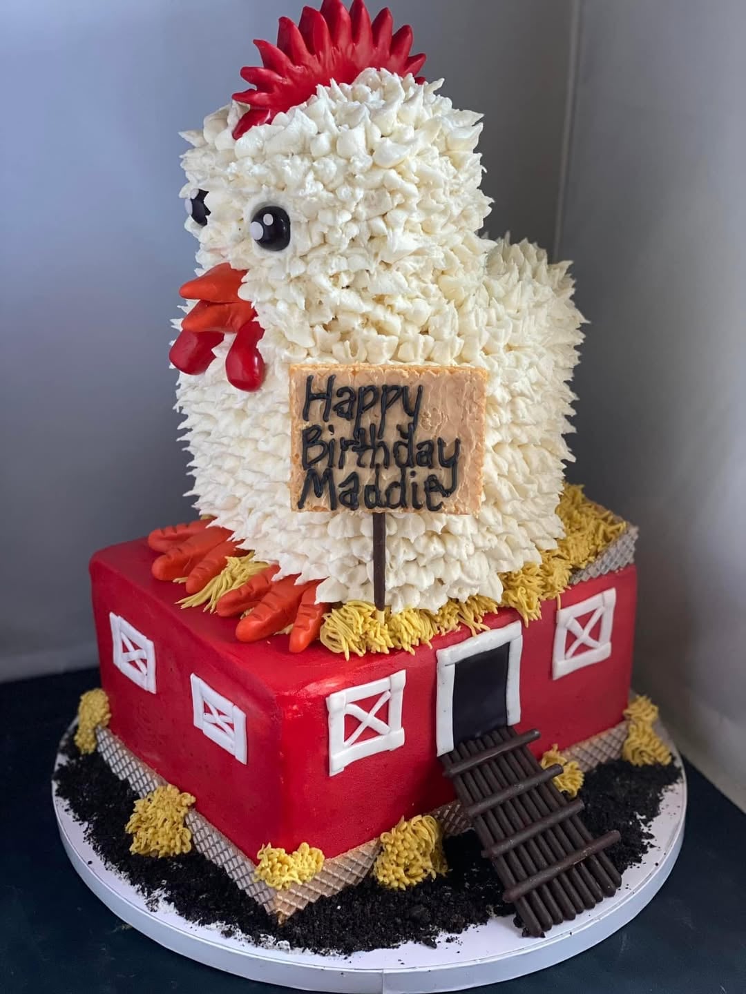 A custom-designed chicken-shaped birthday cake perched on a bright red coop, made by OhMyGoodies in Topeka, KS.