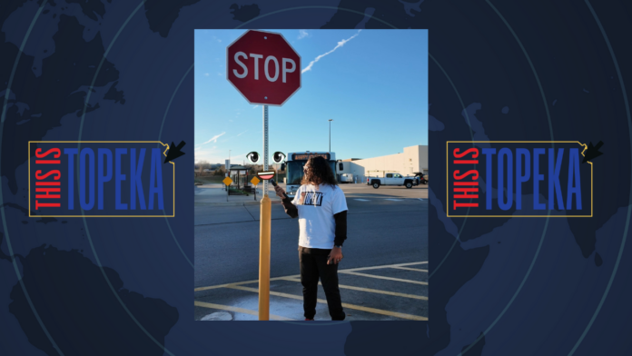 Reporter interviews a battered stop sign in a Topeka Walmart parking lot, symbolizing its struggle against reckless drivers.