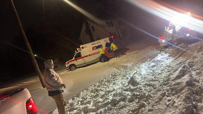 Local hero assists a stuck ambulance during a snowstorm in Topeka, using a tow truck to help navigate icy roads.